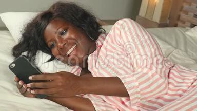 美丽<strong>的</strong>美国黑人女士，穿着睡衣，躺着，<strong>轻松的</strong>微笑，<strong>愉快的</strong>，新鲜<strong>的</strong>使用互联网手机网络